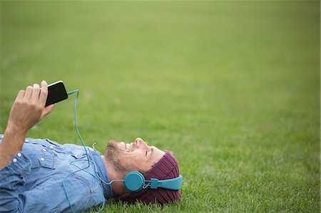 Man listening to headphones on lawn Stockbilder - Premium RF Lizenzfrei, Bildnummer: 6113-07542412