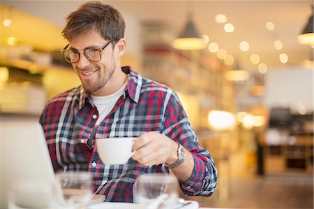 Man using laptop and drinking coffee in cafe Foto de stock - Sin royalties Premium, Código: 6113-07542425