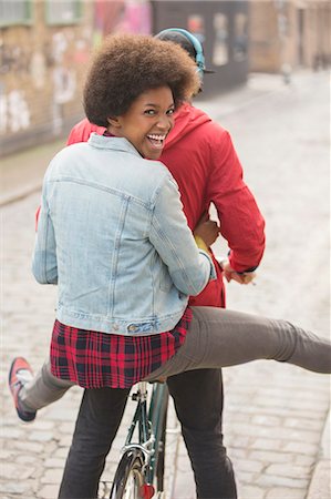 Couple riding bicycle together on city street Stock Photo - Premium Royalty-Free, Code: 6113-07542438