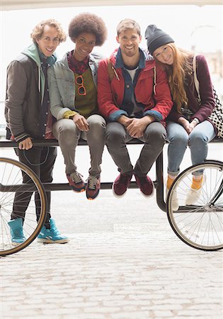 simsearch:6113-07542497,k - Friends smiling together on urban bike rack Photographie de stock - Premium Libres de Droits, Code: 6113-07542542