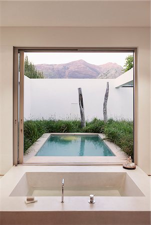 Modern bathroom overlooking swimming pool and mountains Foto de stock - Sin royalties Premium, Código: 6113-07542746