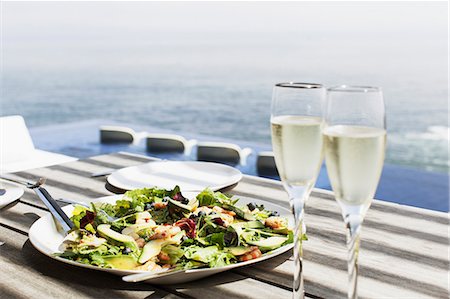 piscine à débordement - Plate of salad and glasses of champagne on table outdoors Photographie de stock - Premium Libres de Droits, Code: 6113-07542700