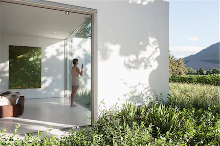 simsearch:6122-07702538,k - Woman standing at window in modern house Photographie de stock - Premium Libres de Droits, Code: 6113-07542707