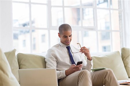 simsearch:6113-07543488,k - Businessman using cell phone on sofa Stock Photo - Premium Royalty-Free, Code: 6113-07542884