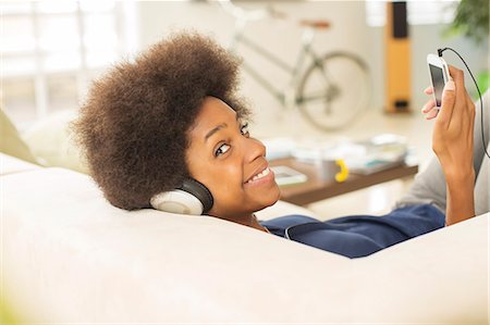 Woman listening to headphones on sofa Stock Photo - Premium Royalty-Free, Code: 6113-07542818