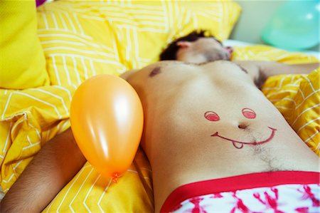 Man with smiley face drawing on belly sleeping after party Foto de stock - Sin royalties Premium, Código: 6113-07542977