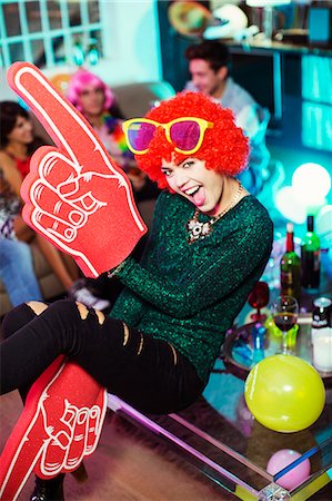 Woman wearing wig, oversized sunglasses and foam finger Stock Photo - Premium Royalty-Free, Code: 6113-07543049