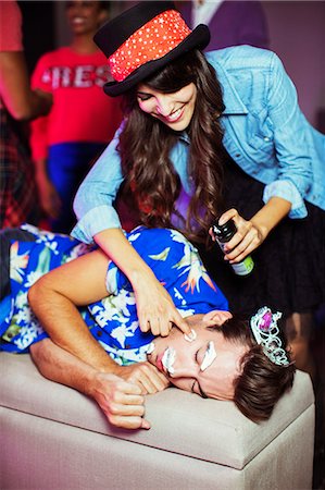 Woman spraying shaving cream on sleeping man's face at party Stock Photo - Premium Royalty-Free, Code: 6113-07543071
