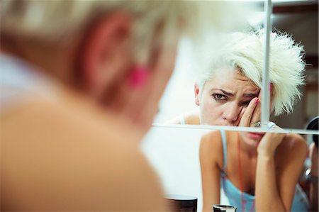 sad woman with short hair - Hungover woman examining herself in mirror Stock Photo - Premium Royalty-Free, Code: 6113-07543001