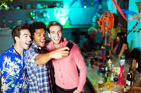 Men taking self-portraits with camera phone at party Foto de stock - Sin royalties Premium, Código: 6113-07543012