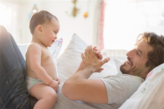 Father playing with baby son on sofa Stock Photo - Premium Royalty-Free, Image code: 6113-07543228