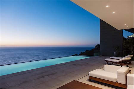 piscina a sfioro - Modern patio and infinity pool overlooking ocean at sunset Fotografie stock - Premium Royalty-Free, Codice: 6113-07543351