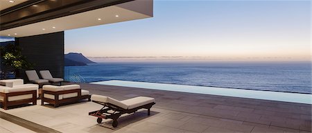 simsearch:6113-07543355,k - Modern patio and infinity pool overlooking ocean at sunset Photographie de stock - Premium Libres de Droits, Code: 6113-07543352