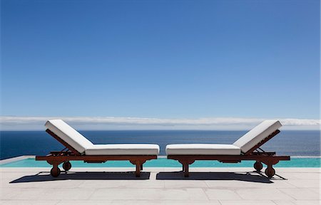 Lounge chairs and infinity pool overlooking ocean Photographie de stock - Premium Libres de Droits, Code: 6113-07543357