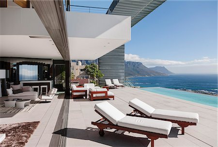 piscina a sfioro - Modern patio and infinity pool overlooking ocean Fotografie stock - Premium Royalty-Free, Codice: 6113-07543356