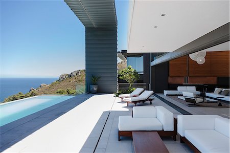 Lounge chairs and infinity pool on modern patio overlooking ocean Foto de stock - Sin royalties Premium, Código: 6113-07543375