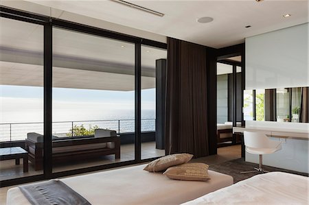 simsearch:6113-07648957,k - Modern bedroom and balcony overlooking ocean Photographie de stock - Premium Libres de Droits, Code: 6113-07543307
