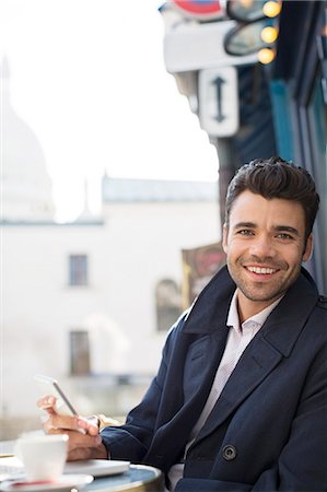 Businessman using cell phone at sidewalk cafe Stock Photo - Premium Royalty-Free, Code: 6113-07543463