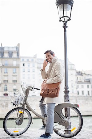 publicidad - Businessman talking on cell phone on bicycle along Seine River, Paris, France Foto de stock - Sin royalties Premium, Código: 6113-07543476