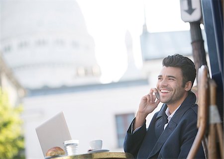 photografia - Businessman talking on cell phone at sidewalk cafe near Sacre Coeur Basilica, Paris, France Foto de stock - Royalty Free Premium, Número: 6113-07543488