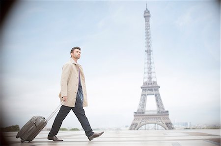 full body businessman outside - Businessman pulling suitcase near Eiffel Tower, Paris, France Stock Photo - Premium Royalty-Free, Code: 6113-07543494