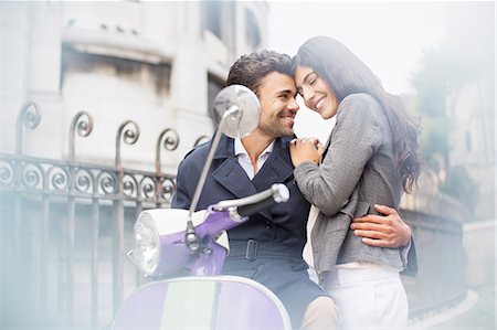 Couple hugging on scooter on city street Stock Photo - Premium Royalty-Free, Code: 6113-07543646