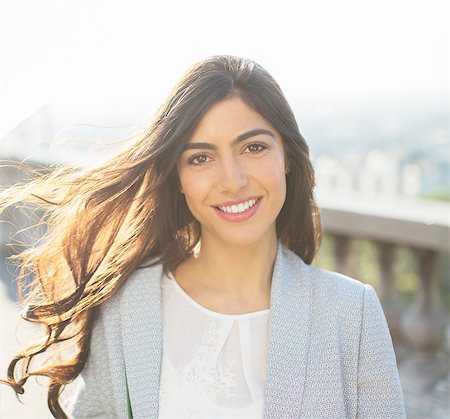 eye contact portrait - Wind blowing long hair of woman smiling outdoors Stock Photo - Premium Royalty-Free, Code: 6113-07543608