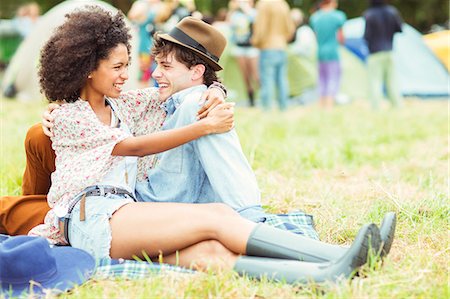 simsearch:6113-07564730,k - Couple hugging in grass outside tents at music festival Foto de stock - Sin royalties Premium, Código: 6113-07564777