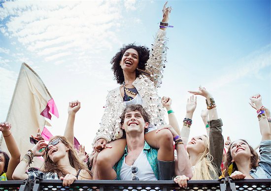 Cheering woman on man's shoulders at music festival Stock Photo - Premium Royalty-Free, Image code: 6113-07564849