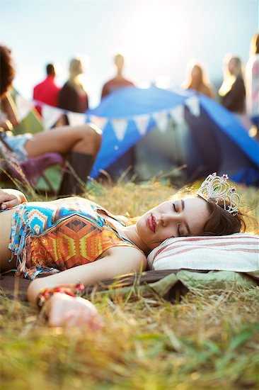 Woman in tiara sleeping outside tent at music festival Stock Photo - Premium Royalty-Free, Image code: 6113-07564873