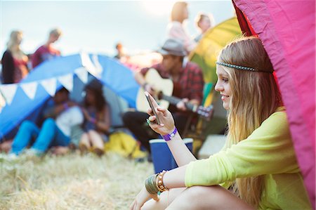 photos, social media - Woman text messaging with cell phone at tent at music festival Stock Photo - Premium Royalty-Free, Code: 6113-07564870