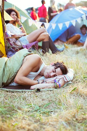 Man in sleeping bag sleeping outside tents at music festival Stock Photo - Premium Royalty-Free, Code: 6113-07564876