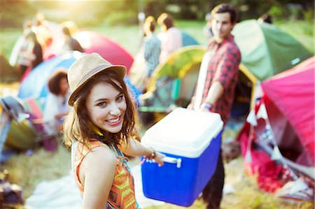 summer camping - Portrait of woman helping man carry cooler outside tents at music festival Stock Photo - Premium Royalty-Free, Code: 6113-07564893