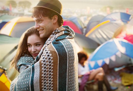 Couple wrapped in a blanket outside tents at music festival Stock Photo - Premium Royalty-Free, Image code: 6113-07564899