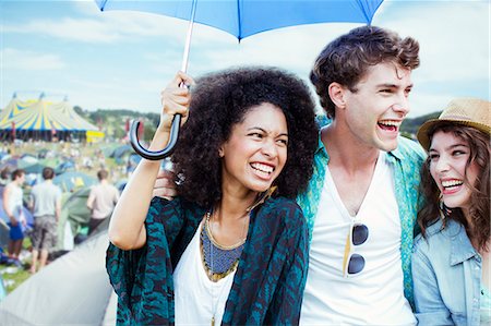 Friends with umbrella at music festival Stock Photo - Premium Royalty-Free, Code: 6113-07564829