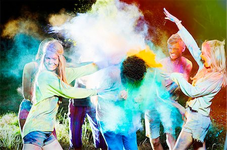 roupa tingida - Friends throwing chalk dye on man at music festival Foto de stock - Royalty Free Premium, Número: 6113-07564903