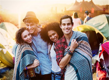 Portrait of couples wrapped in a blanket outside tents at music festival Stock Photo - Premium Royalty-Free, Code: 6113-07564900