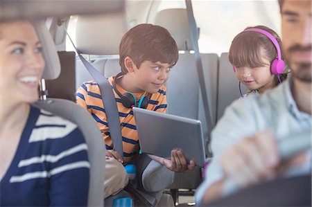 Brother and sister sharing digital tablet in back seat of car Stock Photo - Premium Royalty-Free, Code: 6113-07564930