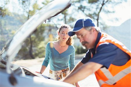 side of the road - Woman watching roadside mechanic check car engine Stock Photo - Premium Royalty-Free, Code: 6113-07565046