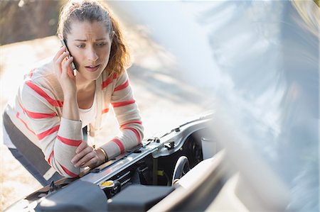 Frustrated woman talking on cell phone and looking at car engine at roadside Stock Photo - Premium Royalty-Free, Code: 6113-07565070