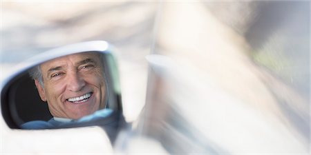 Reflection of smiling senior man in side-view car mirror Stock Photo - Premium Royalty-Free, Code: 6113-07565021