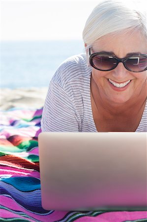 sunglasses women - Happy woman using laptop on beach Stock Photo - Premium Royalty-Free, Code: 6113-07565151