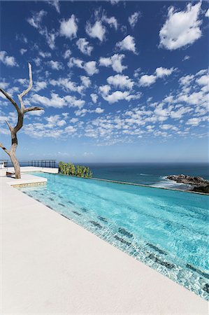 Clouds in blue sky over luxury lap pool overlooking ocean Stock Photo - Premium Royalty-Free, Code: 6113-07565195