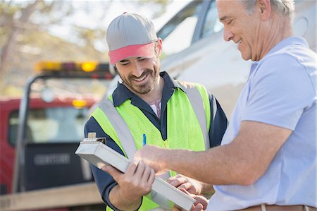 simsearch:6113-07565071,k - Man signing paperwork for roadside mechanic Stock Photo - Premium Royalty-Free, Code: 6113-07565114