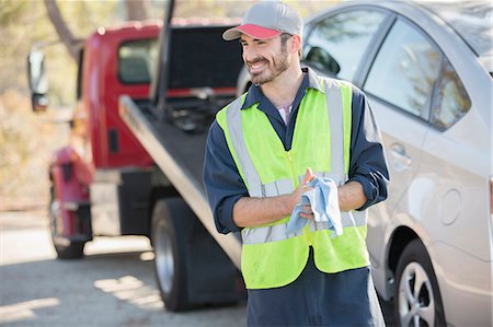 Roadside mechanic wiping hands with cloth next to tow truck Stock Photo - Premium Royalty-Free, Code: 6113-07565134