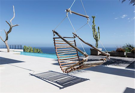 simsearch:6113-07147544,k - Hanging wooden chair on luxury patio overlooking ocean Photographie de stock - Premium Libres de Droits, Code: 6113-07565205