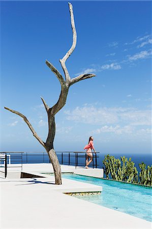 simsearch:6113-07565224,k - Woman standing on poolside balcony overlooking ocean Stock Photo - Premium Royalty-Free, Code: 6113-07565210