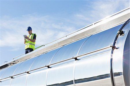 Worker using digital tablet on platform above stainless steel milk tanker Photographie de stock - Premium Libres de Droits, Code: 6113-07565396