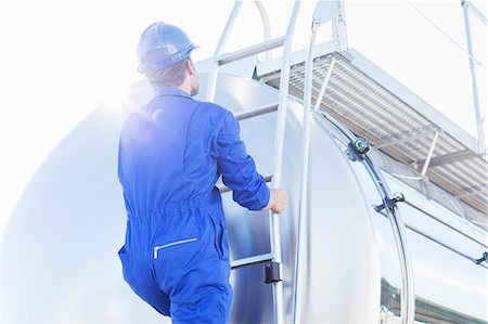 simsearch:6113-07565437,k - Worker climbing ladder at back of stainless steel milk tanker Foto de stock - Sin royalties Premium, Código: 6113-07565433