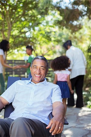 portrait happy latin family - Portrait of smiling senior man on patio with family in background Stock Photo - Premium Royalty-Free, Code: 6113-07565542